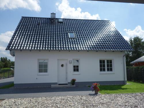 una pequeña casa blanca con techo negro en Feldstrasse 3 b en Zempin