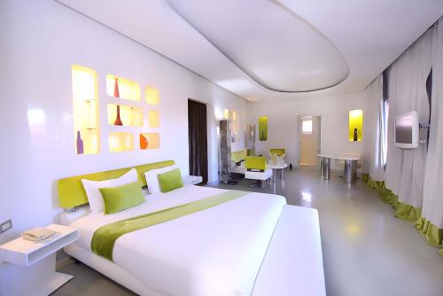 Sky Boutique Ennahda Rennaissance في مراكش: غرفة نوم بيضاء مع سرير وطاولات بيضاء كبيرة