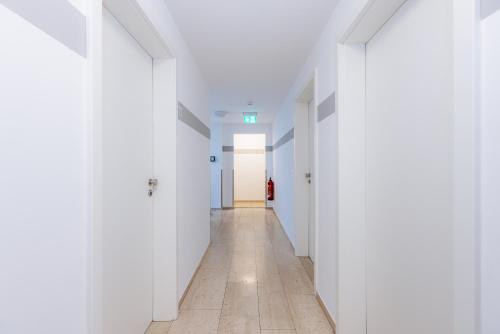an empty corridor with white walls and a hallway with white doors at Hotel Villa Positano in Riedstadt