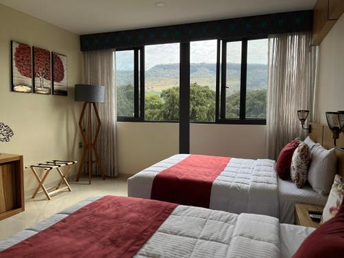a hotel room with two beds and a large window at Hotel Cinco Diamantes in Atotonilco el Alto