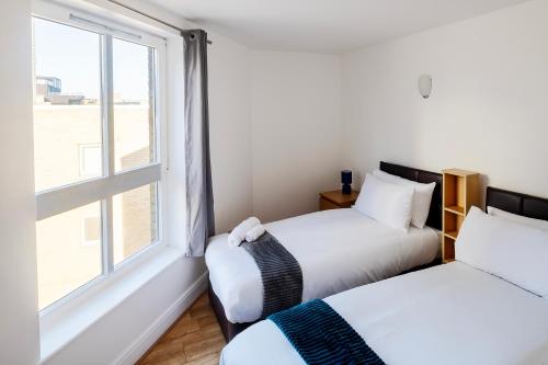two beds in a room with a window at The Bright Flat in Whitechapel in London
