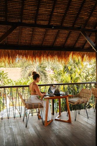 a woman sitting at a table with a laptop at Hani Hideaway in Gili Air