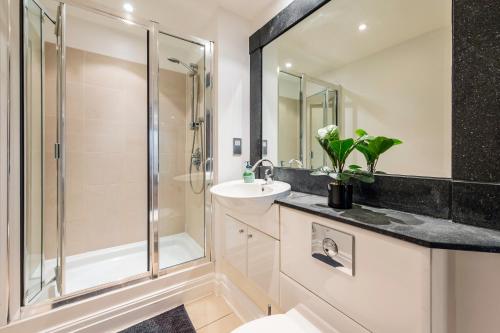 a bathroom with a glass shower and a sink at Modern Paddington Station 2 Bedroom Apartment in London