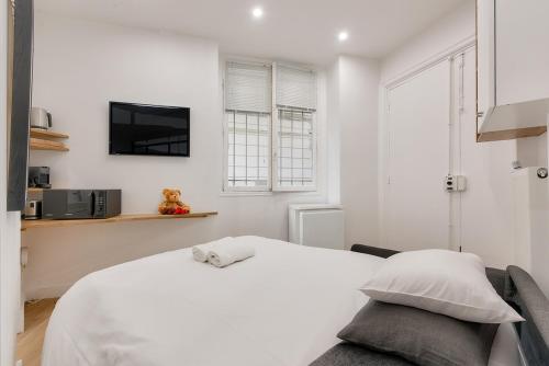 une chambre blanche avec un lit et une télévision dans l'établissement 165 - Urban Studio near Haussmann Boulevard, à Paris