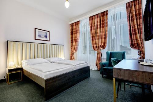 Schlafzimmer mit einem Bett, einem Schreibtisch und einem Stuhl in der Unterkunft Hotel Maxim in Marienbad