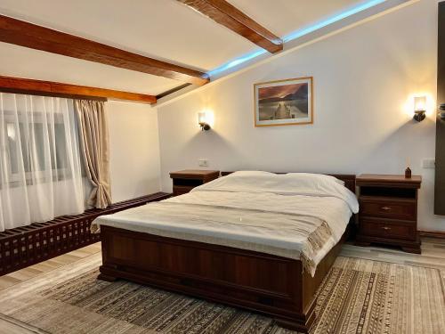 ein Schlafzimmer mit einem Bett, zwei Nachttischen und einem Fenster in der Unterkunft Parc Vatra Dornei 1 - Family, couples & groups in Vatra Dornei