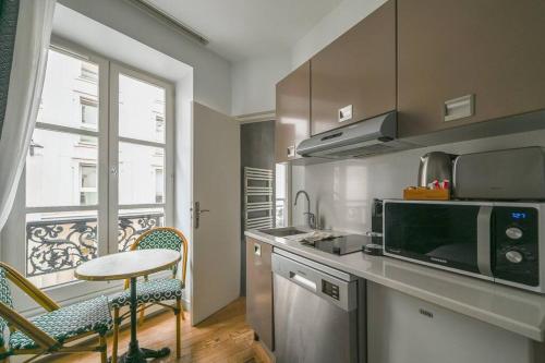 Il comprend une cuisine équipée d'un four micro-ondes, d'une table et de chaises. dans l'établissement Paris, Opéra 2D...pour un séjour magique, à Paris