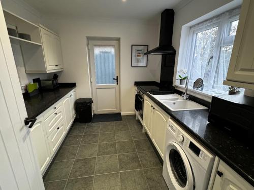 a kitchen with white cabinets and a sink at Station house in Ramsgate