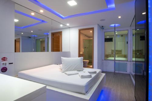 1 dormitorio con cama blanca y luces azules en Motel fantasy 4 (adult Only), en Belo Horizonte