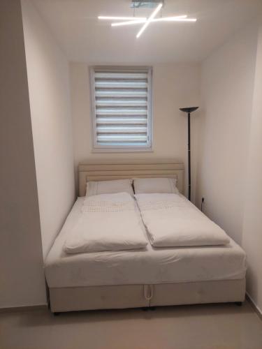 a bed in a white room with a window at Apartman Magus in Tuzla