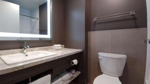 La salle de bains est pourvue d'un lavabo, de toilettes et d'un miroir. dans l'établissement Hôtel-Motel Normandin Alma, à Alma