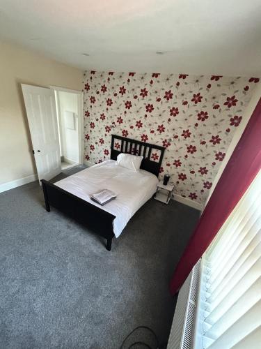 a bedroom with a bed with a floral wallpaper at Canvas House in Carlisle