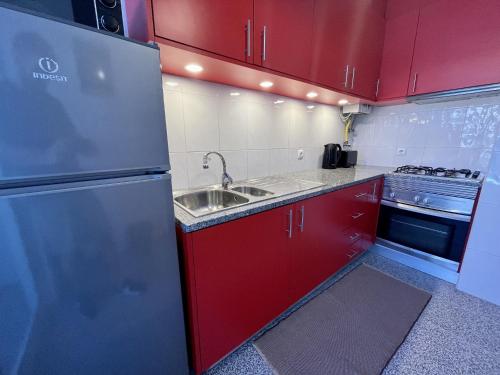 a kitchen with red cabinets and a stainless steel refrigerator at Onda Beach House in Cortegaça