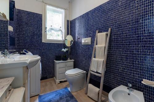 Baño de azulejos azules con aseo y lavamanos en Casa Isola, en Bergeggi