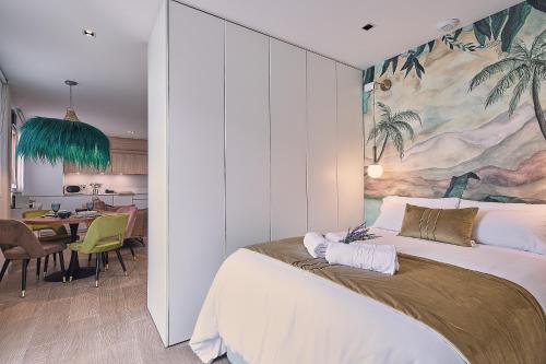 1 dormitorio con 1 cama grande y una pintura en la pared en La Terraza de Lulú Little Apartments en Cádiz