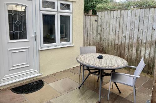 a patio with a table and chairs and a fence at Twin Gates Annexe in Falmouth