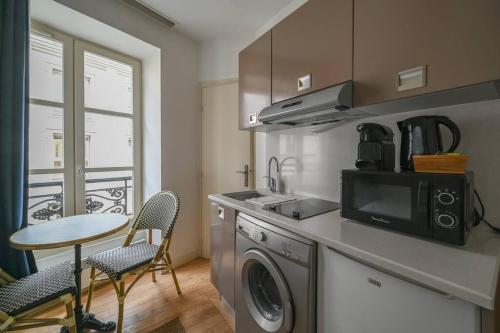 une cuisine avec une machine à laver et une table avec des chaises dans l'établissement So cute Apartment (Opéra 3D), à Paris
