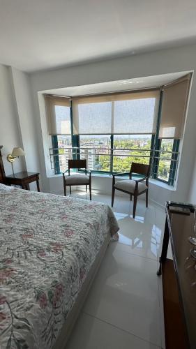 una camera con letto e alcune sedie e finestre di Apartamento Millennium inn a Mendoza