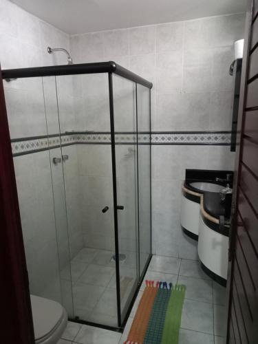 La salle de bains est pourvue d'une douche en verre et de toilettes. dans l'établissement Pousada Aconchego do Tambaú, à João Pessoa