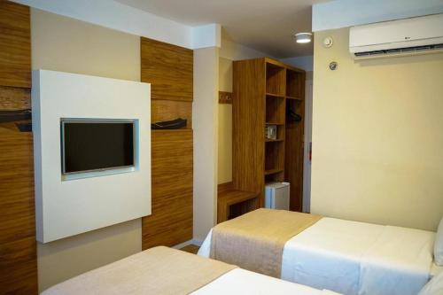Habitación de hotel con 2 camas y TV en Quarto Design Linhares 507, en Linhares