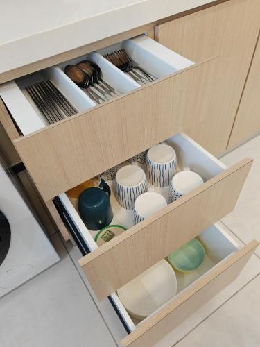an open drawer in a cabinet filled with dishes at Cityscape Haven - Urban Suites by Ocean Luxe in Jelutong