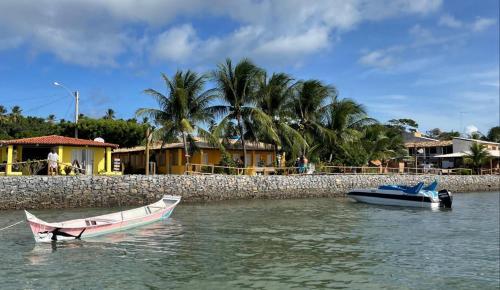 deux bateaux assis dans l'eau à côté d'un mur dans l'établissement Pousada Grão de Areia Beira Mar, à Mangue Seco