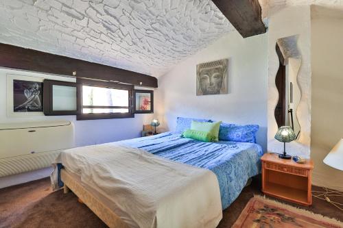 a bedroom with a bed with a blue comforter at Provenzalisches Haus Hannah - Garten mit Meerblick und Pool by Riviera HomeLife in Agay - Saint Raphael