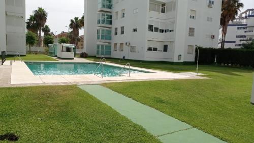 a swimming pool in a yard next to a building at ÁTICO VALDELAGRANA PLAYA - Aire Acondicionado y Piscina in El Puerto de Santa María