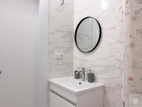 a white bathroom with a sink and a mirror at Renthouse Apartments City Gates #4 in Chişinău