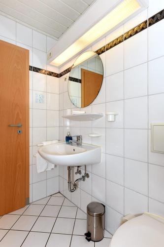 a white bathroom with a sink and a mirror at Hotel garni Poggenstool in Neuharlingersiel