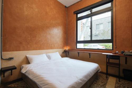 1 dormitorio con cama blanca y ventana en 碄艍 LinJyu en Taitung