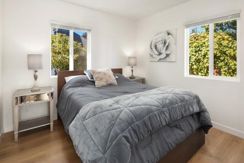 a white bedroom with a bed and two windows at Green Lakefront Villa in Seattle