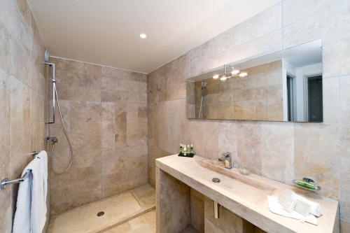 a bathroom with a sink and a shower and a mirror at Moulin de Vernègues Hôtel & Spa in Mallemort