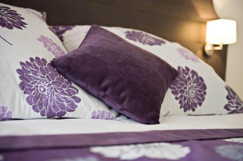 a bed with purple and white pillows on it at Moulin de Vernègues Hôtel & Spa in Mallemort