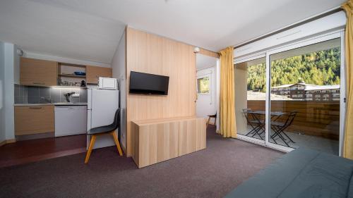 Cette chambre comprend une cuisine et une table avec une télévision. dans l'établissement Chalets du Verdon 2204 Appt ski au pied 6 pers, à La Foux