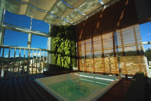 uma banheira de hidromassagem num quarto com uma grande janela em Gontijo Inn Hotel em Itajubá