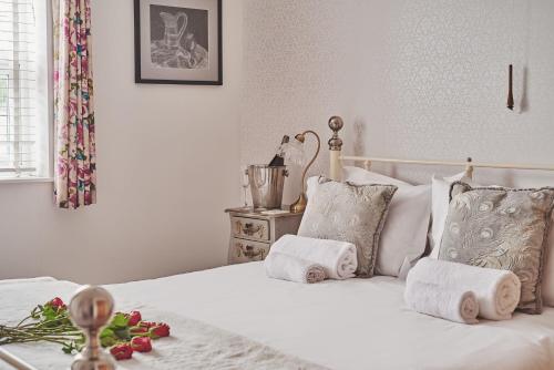 una camera da letto con un letto bianco e asciugamani di Oakey Cottage a Bourton on the Water