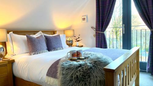 a bedroom with a bed with a large window at Bluebell Cottage with Hot Tub in Ballachulish