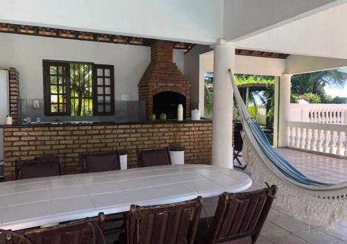 d'une terrasse avec une table, un hamac et une cheminée. dans l'établissement Casa de praia, à Caucaia