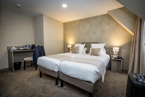 a hotel room with a large bed and a desk at H&ocirc;tel De Brunville & Spa in Bayeux