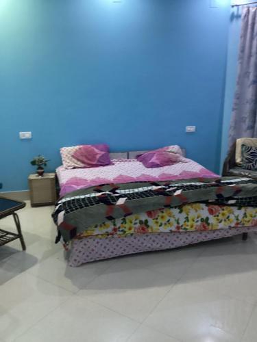 a bed in a room with a blue wall at Trikuta Homestay in Jammu