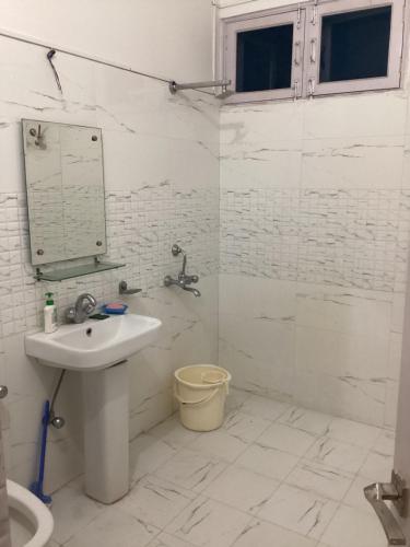 La salle de bains blanche est pourvue d'un lavabo et d'une douche. dans l'établissement Trikuta Homestay, à Jammu