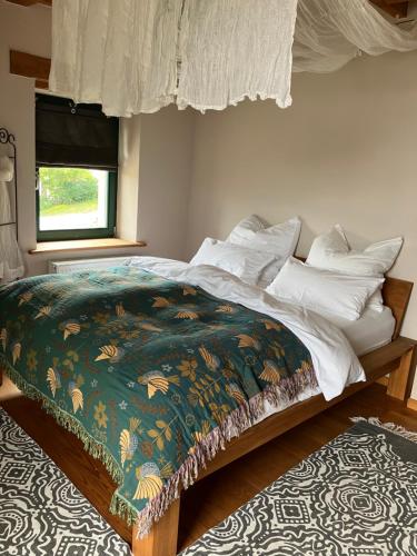 een bed met een groen en wit dekbed en een raam bij Landhaus Ana-Vital in Merzig
