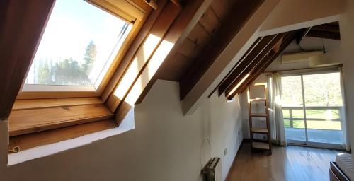 um quarto com uma grande janela e piso em madeira em Chacra Esaki em El Bolsón
