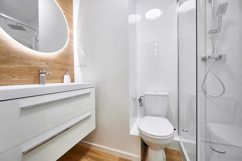 y baño blanco con aseo y ducha. en Apartament Kawa u Piłsudskiego, en Olsztyn