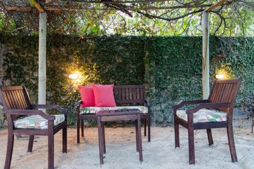 two benches with red pillows on them in front of a hedge at Casa Bia in Jericoacoara