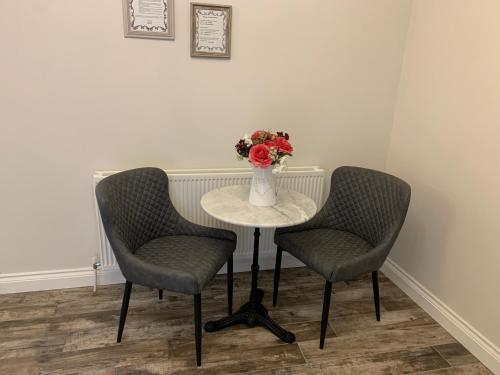 two chairs and a table with a vase of flowers at Millbrae Lodges in Belfast