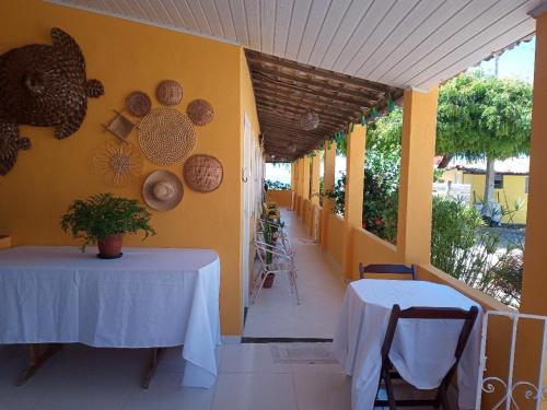 Deux tables sur le côté d'une pièce aux murs jaunes dans l'établissement Pousada Grão de Areia Beira Mar, à Mangue Seco
