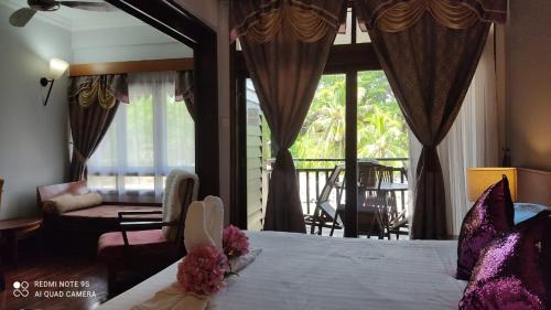 a bedroom with a bed and a living room with windows at Villa Dalam laut 530 in Pantai Cenang