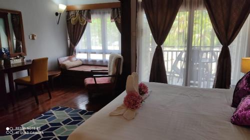 a hotel room with a bed with flowers on it at Villa Dalam laut 530 in Pantai Cenang